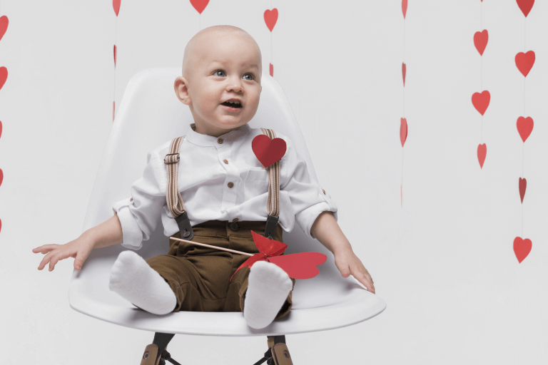 Happy baby in a safe Valentine’s Day setting with heart decorations